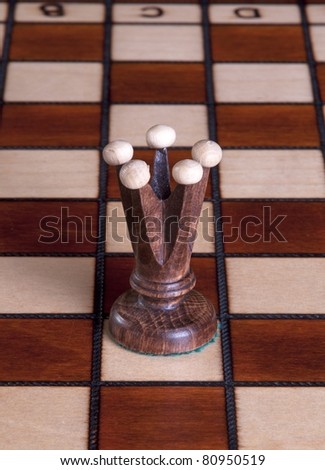 Queen chess piece made of wood, on a chess board