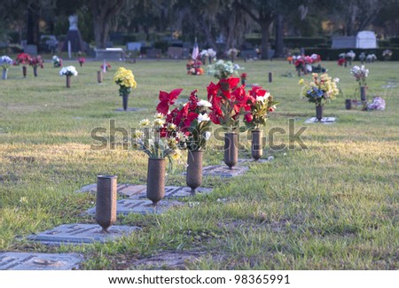 Graves and tombstones at a cemetery. Flowers and vases