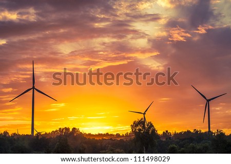 A silhouette of windturbines on a amazing sunset