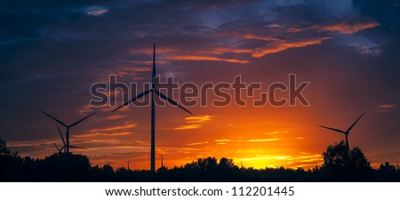A silhouette of windturbines on a amazing sunset