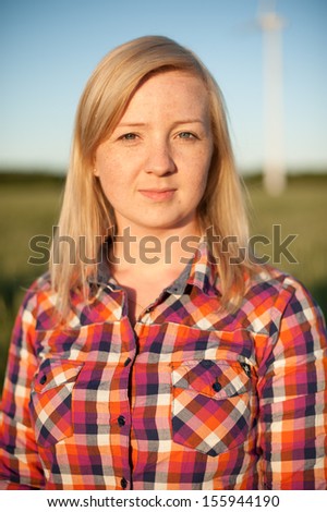 portrait of freckled blonde outside wearing a plaid shirt