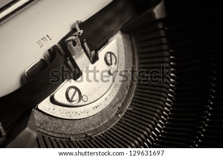 A Closeup image of the typebars and ribbon of an old style typewriter and paper with the letters: NB! (Shallow Depth of Field)