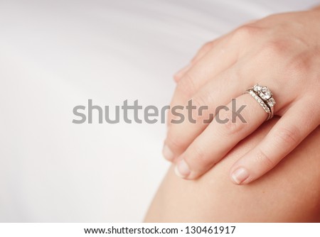 Hand of a caucasian adult woman with a diamond engagement ring on her left ring finger