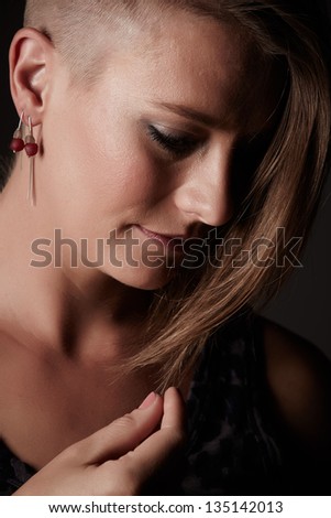 Beautiful young adult blonde caucasian woman with an funky modern hair cut on a neutral background