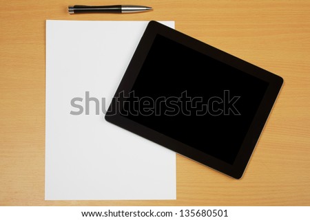 Paper, pen and tablet computer on wooden textured brown desk with copy space and clean paper to create own text..
