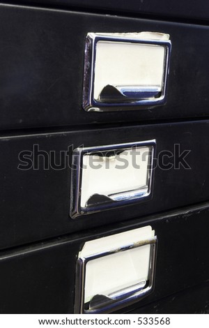 Close-up of a black mini filing cabinet and label with three closed drawers