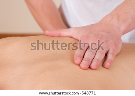 Woman lying on massage table with the hands of male masseuse on her back
