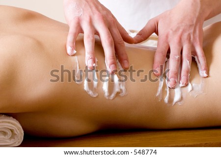 Woman lying on massage table with the hands of male masseuse on her back