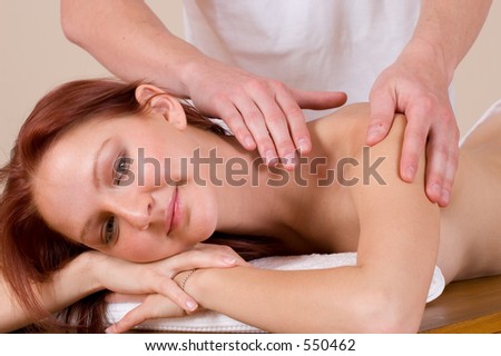 Woman lying on massage table with the hands of male masseuse on her back and shoulders