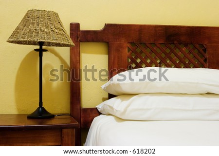 Interior of room with bedside lamps, wooden bed and white duvet cover