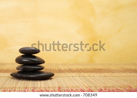 hot stone massaging stones on bamboo cloth in front of wall - copy space