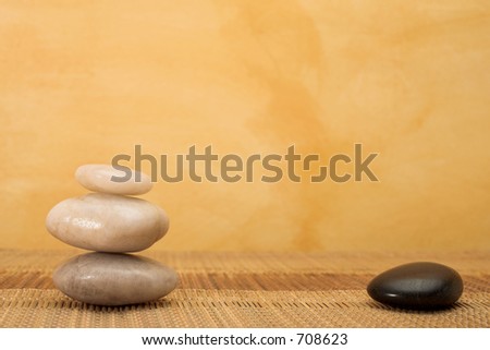 hot stone massaging stones on bamboo cloth in front of wall - copy space