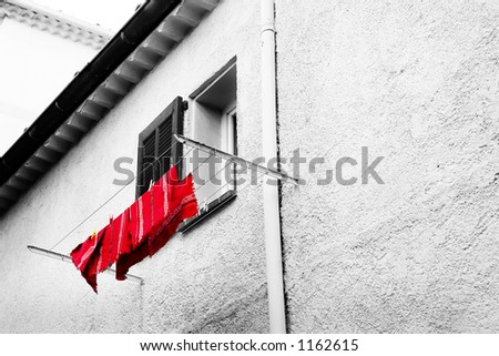 Washing line in front of a window in Antibes, France.  Black and white - only the cloth is red.  Copy space.