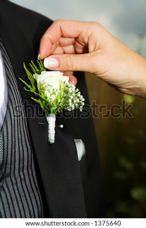 Close-up of Bridal accessories. Hand of bride fixing a Corsage.