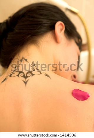 stock photo : Nude woman in a bathroom with tattoo on her back.