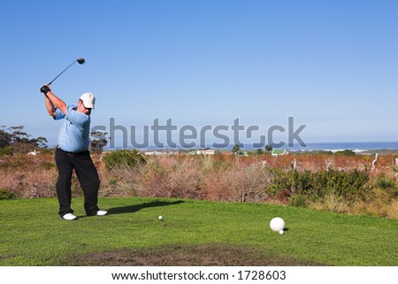 A golfer playing golf on a green.  Movement on golf club, but head is in focus.