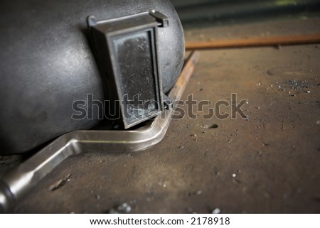 Old welders mask lying on a steel work bench