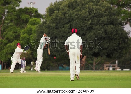 Cricketers playing in the late afternoon, Batsman hitting ball, wicketkeeper trying to catch - Editorial use only