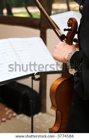 Violinist waiting with music stand in front of her. Holding violin in one hand