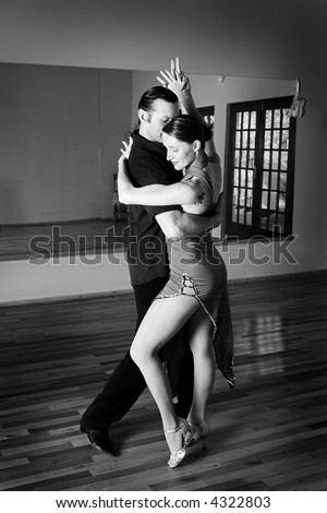 A young adult couple dancing and practicing ballroom dancing together in a studio - Focus on woman, Black and white - high key efect
