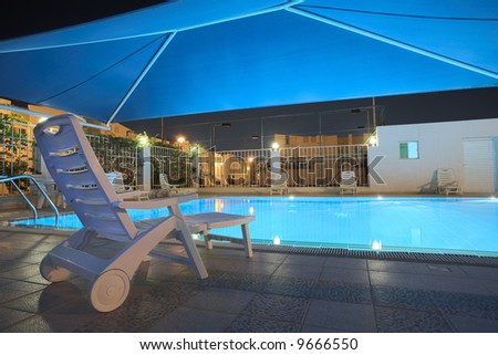 Blue water in a clean swimming pool at night. The pool is covered with a blue shade net roof ? HDR type image