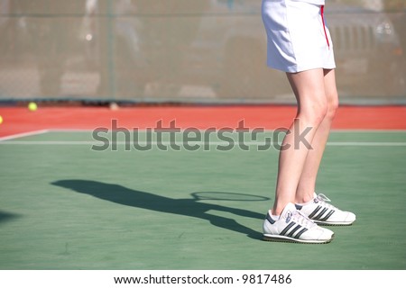 Legs of a young woman playing tennis in the sun