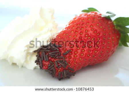 Fresh ripe strawberry with small chocolate sprinkles served as a dessert with a side topping of cream