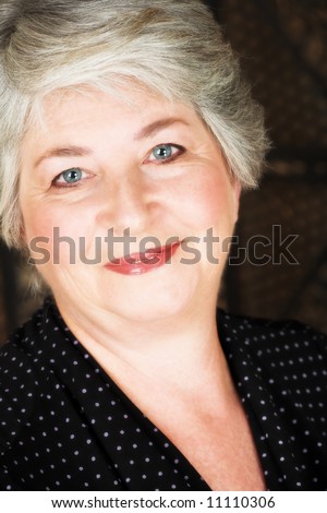 Beatiful older caucasian woman in black blouse, with blue-grey eyes and silver hair.