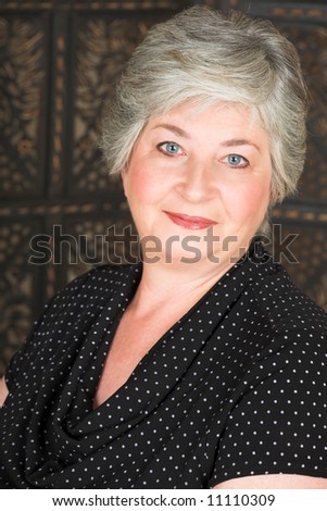 Beatiful older caucasian woman in black blouse, with blue-grey eyes and silver hair.