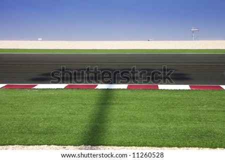Section of astro turf and asphalt next to the Lusail GP and race track. Shadow from lighting system running over track.
