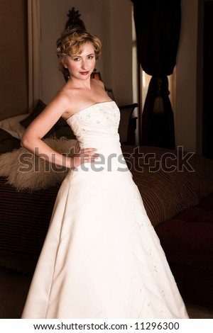 Slim beautiful adult woman with short blonde, curly hair wearing luxurious silk wedding dress on location
