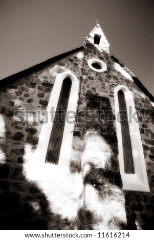 Catholic church building with a cross on the steeple - high key black and white, defocussed