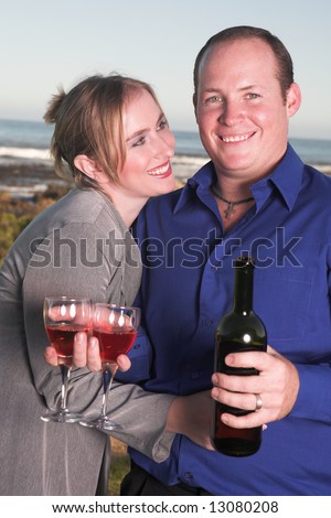 Young adult Caucasian couple drinking wine outdoor next to the ocean