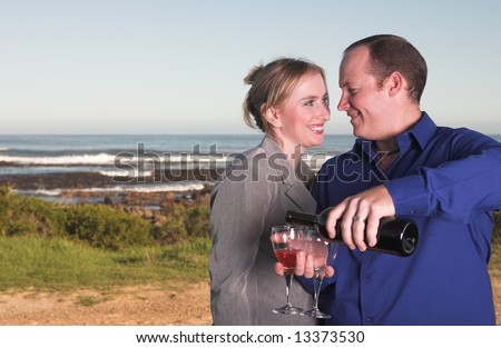 Young adult Caucasian couple drinking wine outdoor next to the ocean