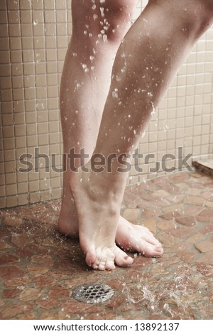 Sexy young adult Caucasian woman with long auburn hair and petite breasts taking a shower in a tile and glass modern bathroom. Part of a series.
