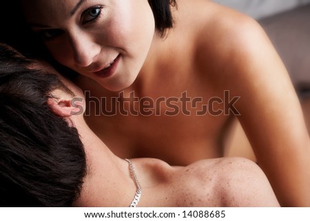 Young adult Caucasian couple in passionate embrace and undressing each other during sexual foreplay. The woman is wearing blue contact lenses