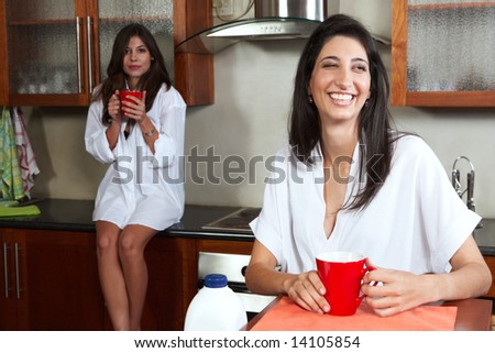 Sexy young adult brunette roommates in lingerie drinking morning coffee in their kitchen before work