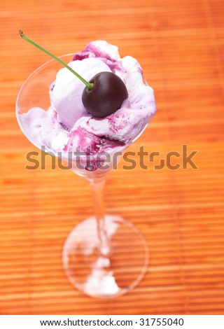 Pink and white cherry Ice-cream with syrup in a tall glass on orange background