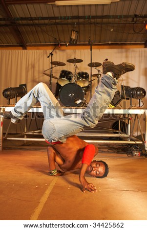 Single African freestyle hip-hop dancer at a training session on stage with instruments in the background