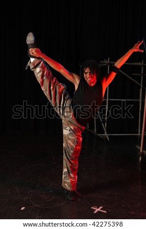 Single African male dancer dancing on the stage with black background during training session. Lit with spotlights