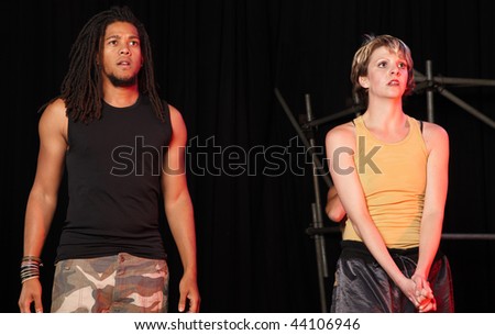A couple of freestyle hip-hop dancers during dance training session on stage. Lit with spotlights