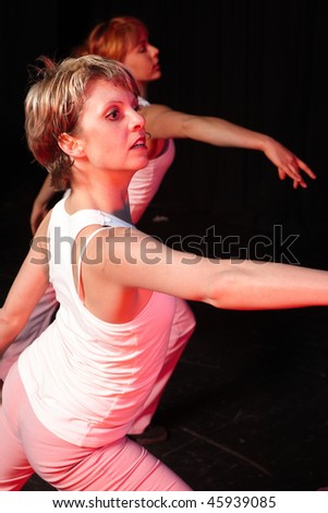 A group of three Caucasian female freestyle hip-hop dancers in a dancing training session. Lit with spotlights