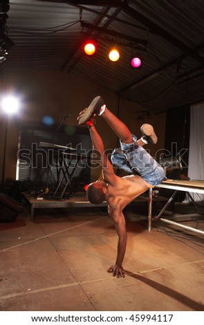 Single freestyle hip-hop dancer in a dancing practice session on stage with instruments. Lit with spotlights. Movement on edges of dancer