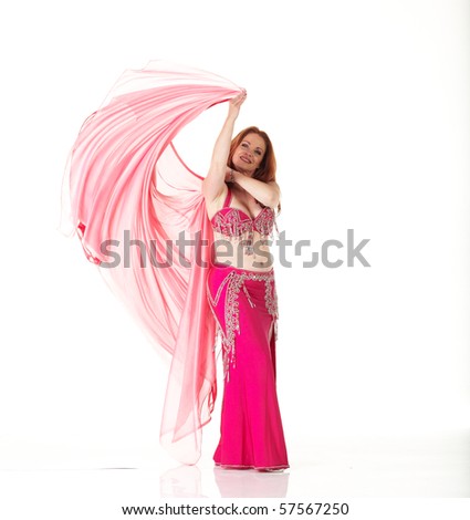 Lithe adult caucasian belly dancer with red hair and pink belly dancing outfit performing a dance with veils on a white background. Not Isolated