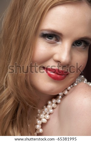 Sexy young caucasian adult woman with red lips and a white pearl necklace around her neck.