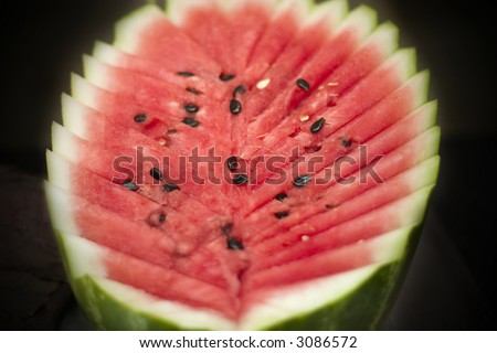 Fresh cut of red juicy watermelon with black seeds. Focus on the center.