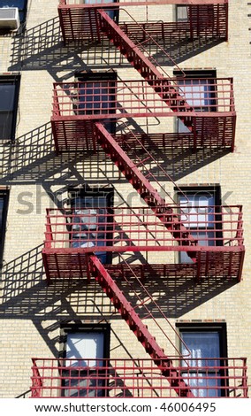 Red fire escape on the light color building with the shadows