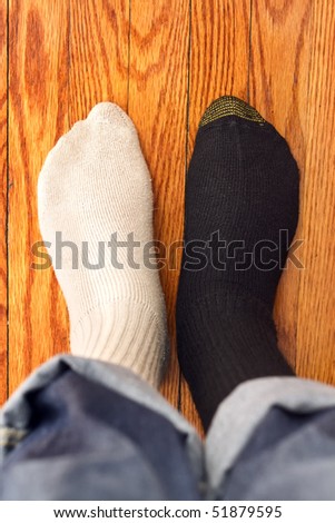 Man in two color socks on the wood floor. Confusing.