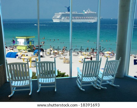 Rocking chairs by the window overlooking a scenic beach resort with a cruise ship passing by