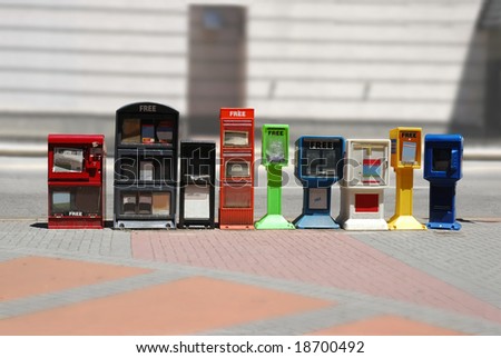 Row of news stands (newspaper dispensers) beside a street by a sidewalk